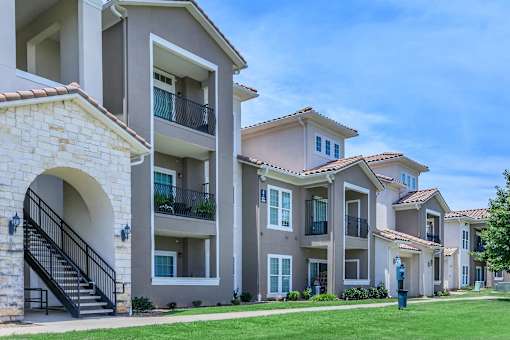 A row of apartment buildings with balconies and a clear blue sky.