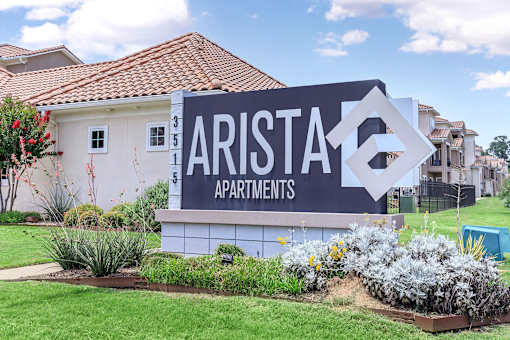 A sign for Arista Apartments is in front of a building.