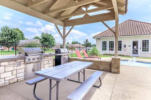 A picnic table is under a canopy next to a pool.