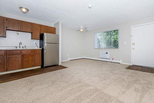A kitchen with a refrigerator, cabinets, and a window.