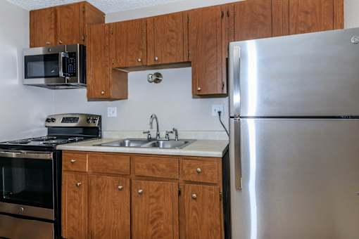A kitchen with a stainless steel refrigerator, microwave, oven, and sink.