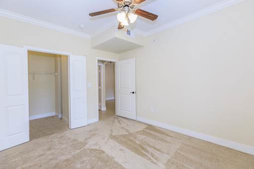 A room with a ceiling fan and carpeted floor.