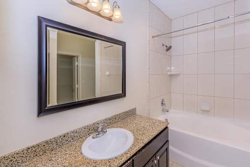 A bathroom with a sink, mirror, and bathtub.