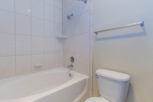 A white toilet sits next to a bathtub in a bathroom.