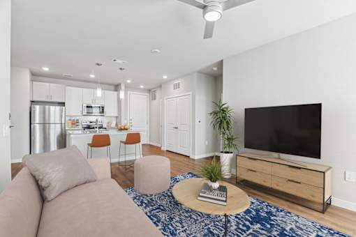 A modern living room with a flat screen TV, a kitchen area, and a dining area.