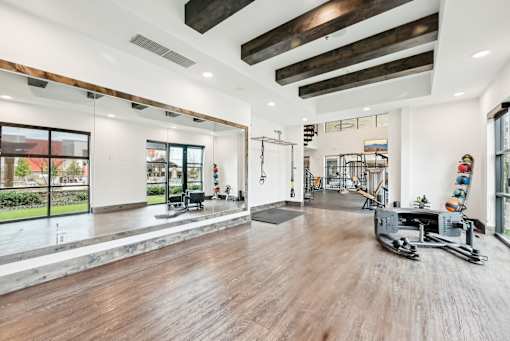 A spacious gym with wooden floors and various exercise equipment.