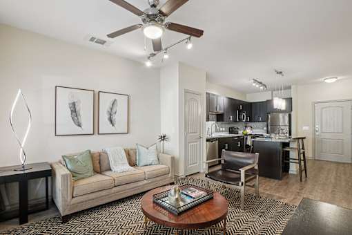 A living room with a couch, coffee table, and a ceiling fan.