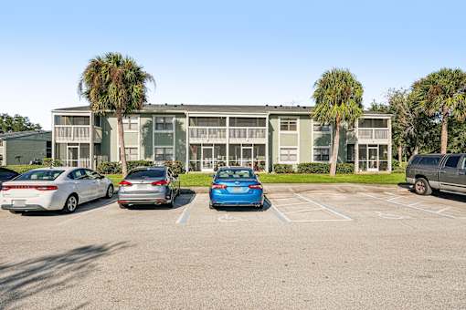 A parking lot with cars and a building in the background.