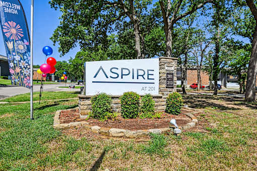 A sign that says "ASPIRE AT 201" is in front of a grassy area.