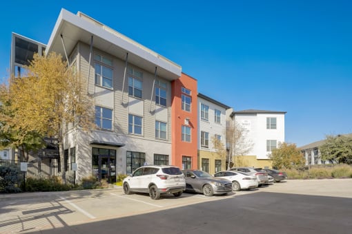 a parking lot with cars in front of an apartment building