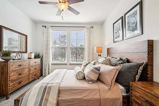 A bedroom with a bed, dresser, and window.