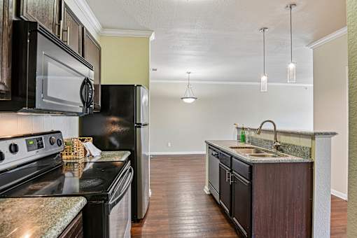 A kitchen with black appliances and a granite countertop.