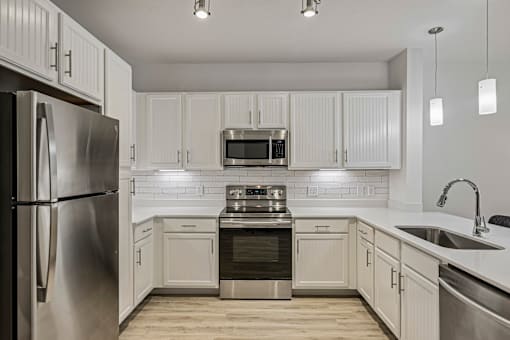 A modern kitchen with white cabinets and stainless steel appliances.