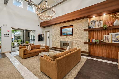 A living room with a stone fireplace and a chandelier.