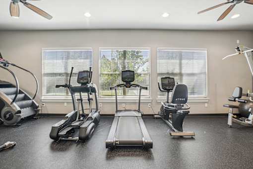 A home gym with a treadmill, elliptical trainer, and stationary bike.