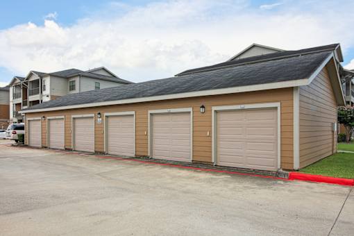 A long building with a black roof and tan siding with a red line in front.