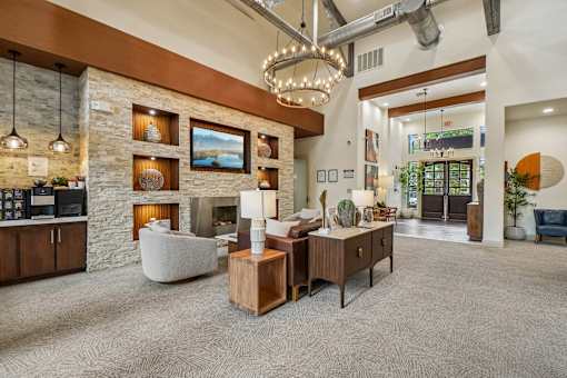 A modern living room with a stone fireplace and a large chandelier.