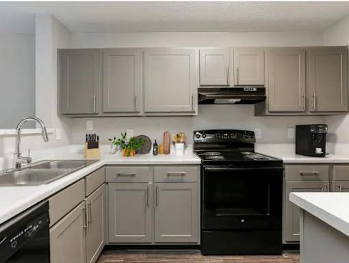 A kitchen with a black stove top oven and white countertops.