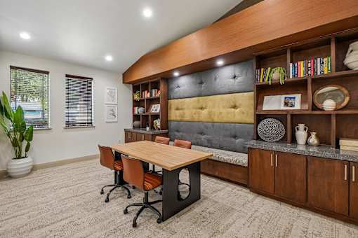A room with a wooden table and chairs, a grey sofa, and a bookshelf with various items.