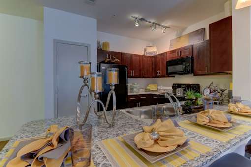 A kitchen with a table set for two with yellow napkins.