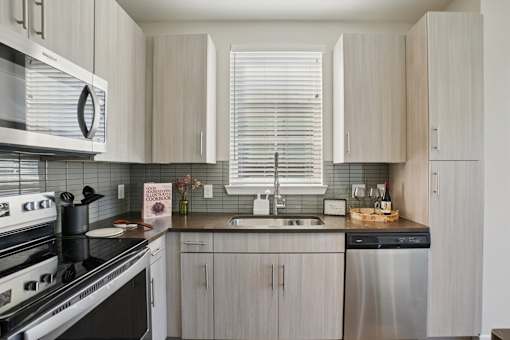 A kitchen with stainless steel appliances and modern, light cabinetry.