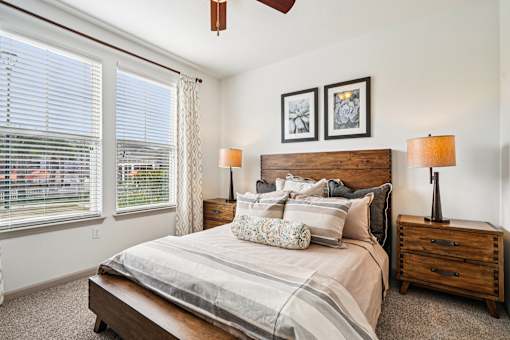 A bedroom with a bed, nightstand, and window with blinds.