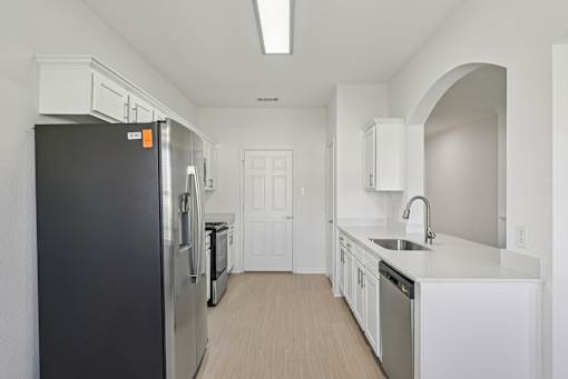 A kitchen with a black fridge and white cabinets.