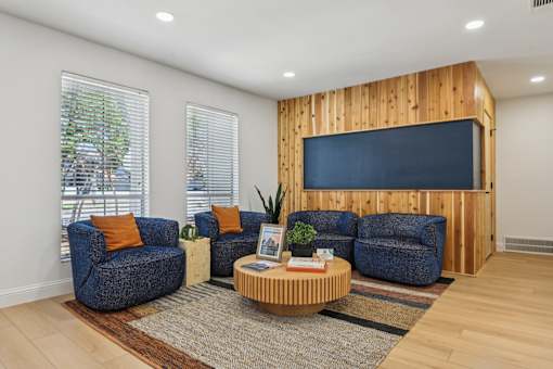 A living room with a blue couch, a wooden coffee table, and a flat screen TV mounted on a wooden wall.