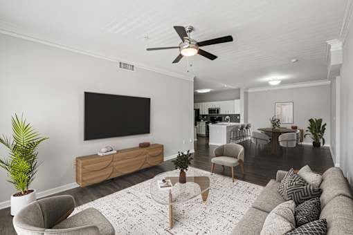 A living room with a grey couch, a coffee table, a flat screen TV, and a ceiling fan.
