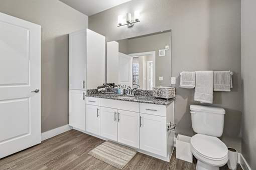 A bathroom with a toilet, sink, and mirror.