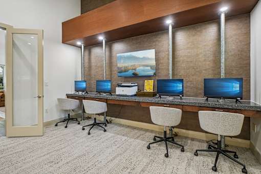 A room with a desk and chairs with a painting on the wall.