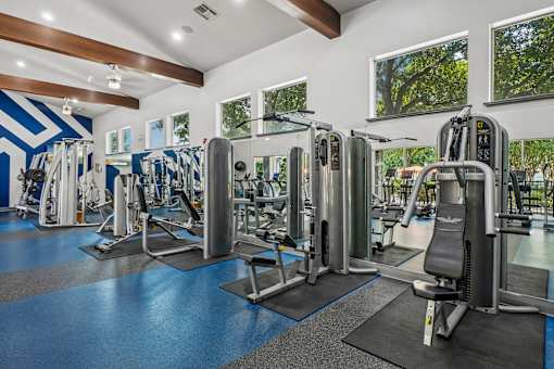 A gym with a variety of equipment including treadmills, weights, and exercise machines.