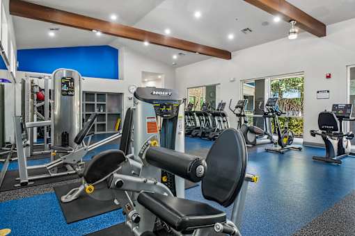 A gym with a variety of equipment including a stationary bike and a leg press machine.