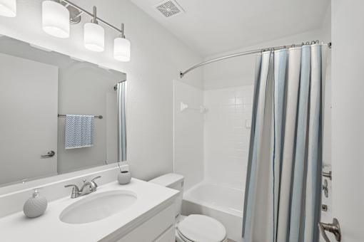 A white bathroom with a toilet, sink, and shower.