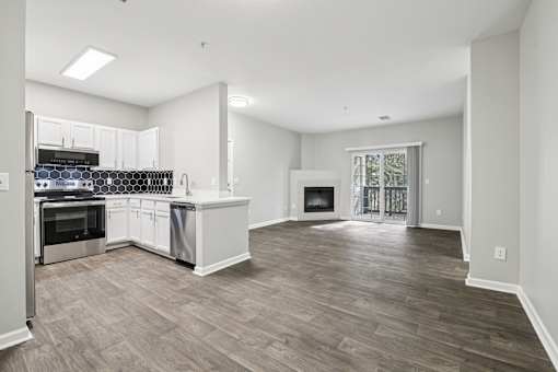 A spacious kitchen with wood flooring and white cabinetry.