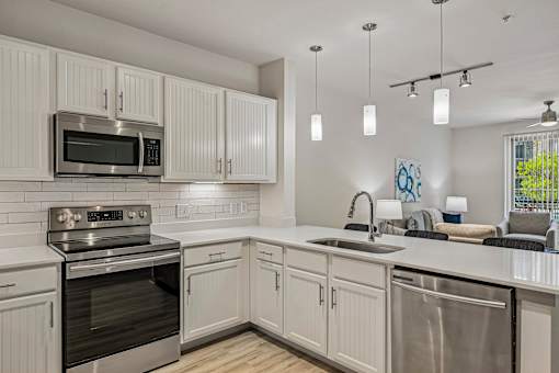 A modern kitchen with white cabinets and stainless steel appliances.