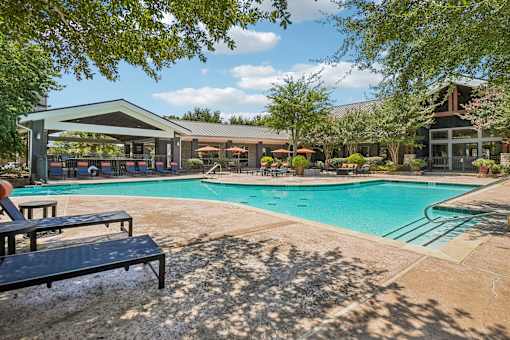 A pool area with a bench and a building in the background.