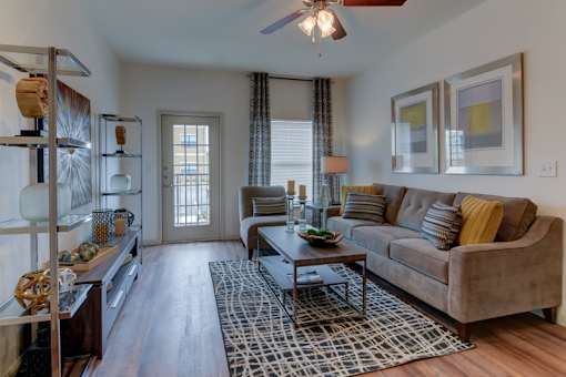 A living room with a brown couch and a black and white rug.