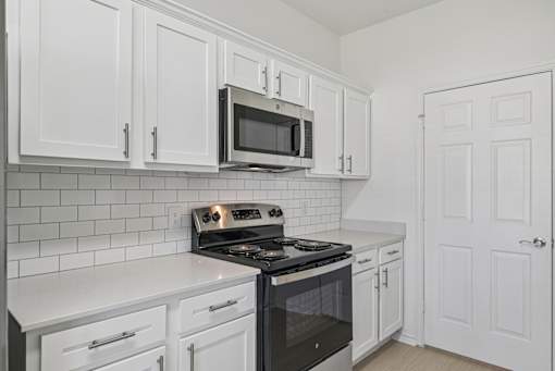 A kitchen with white cabinets and a black stove top oven.
