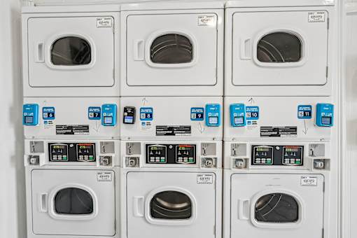 A row of washing machines with the front loading doors open.
