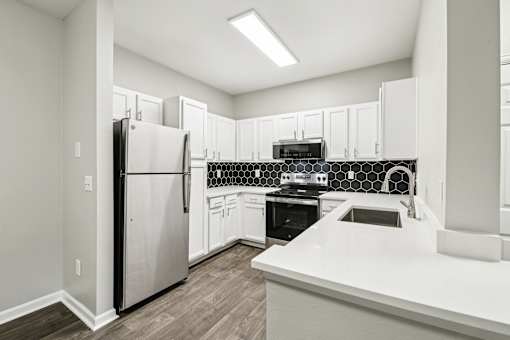 A kitchen with a black refrigerator and white cabinets.