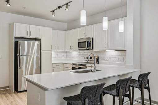 A kitchen with a white countertop and a stainless steel refrigerator.