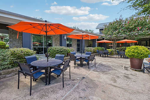 A patio with tables and chairs under orange umbrellas.