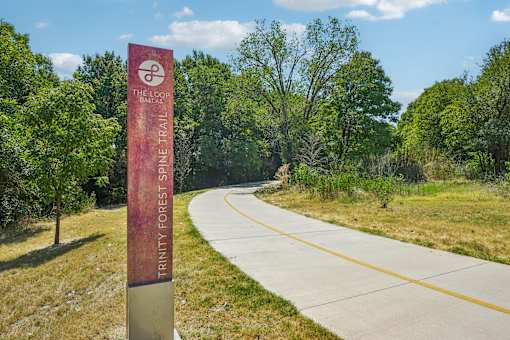 A sign for the Tancy Forest Shine Trail stands in front of a paved road.