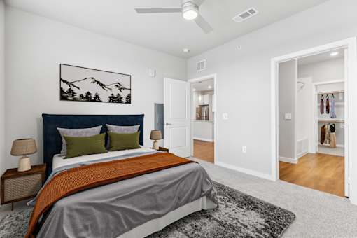 A bedroom with a bed, a rug, and a painting on the wall.