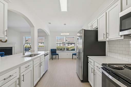 A kitchen with white cabinets and a black refrigerator.