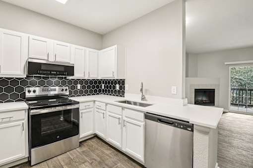 A kitchen with white cabinets and a black and white tiled backsplash.
