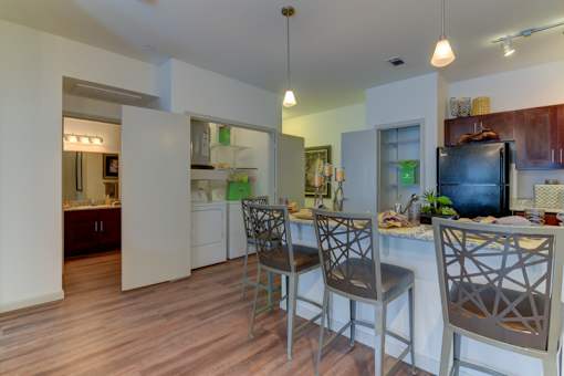 A kitchen with a bar and chairs.