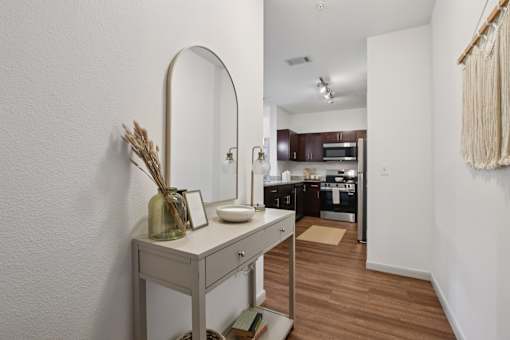 A vanity table with a mirror and a vase with dried flowers on it.