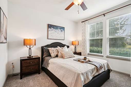 A bedroom with a bed, two lamps, and a painting on the wall.